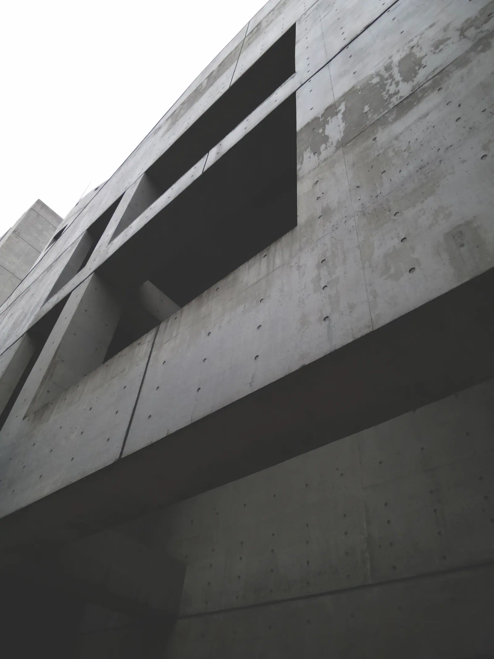 Monochrome concrete facade with deep geometric openings